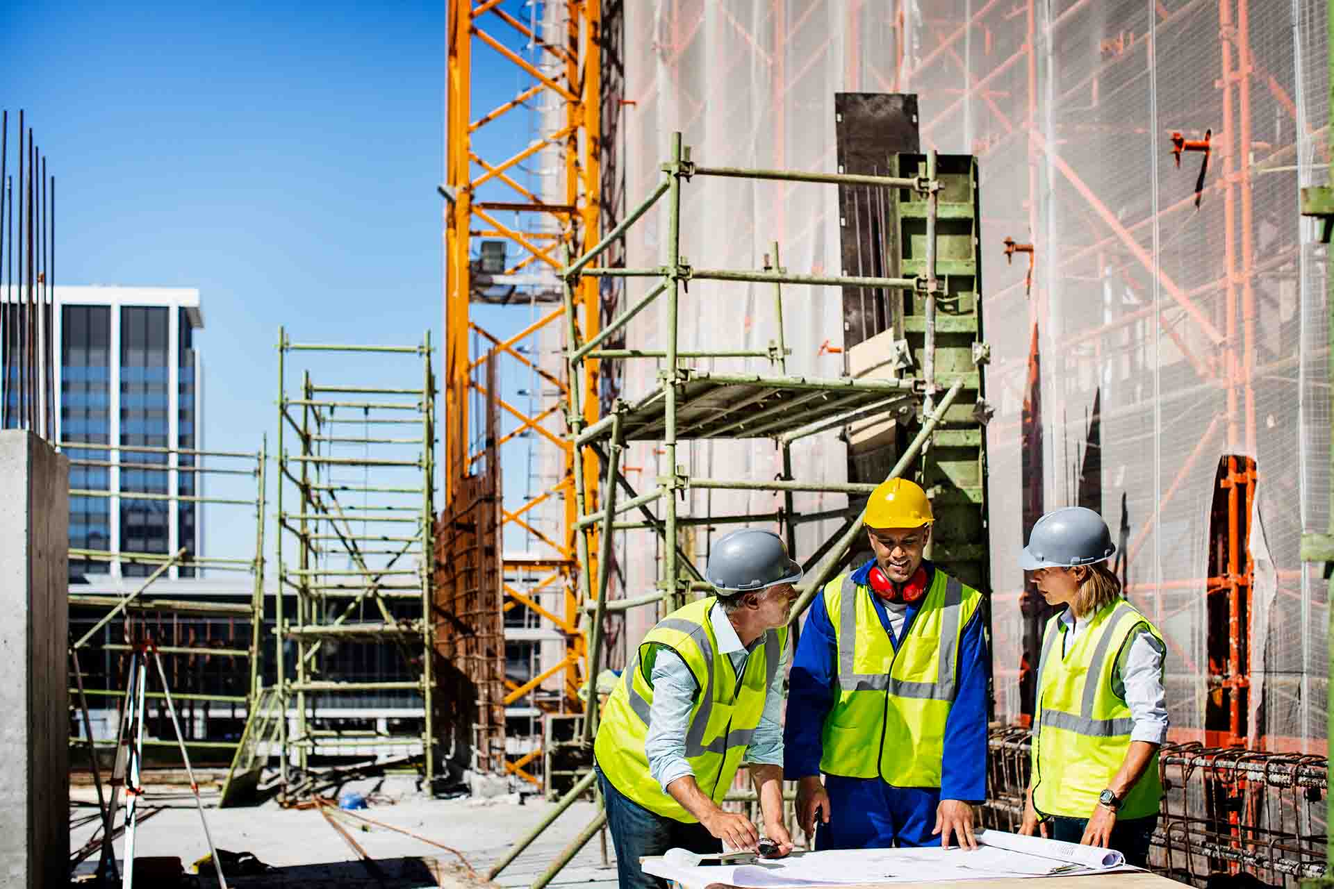 architects and construction workers looking at blueprints on jobsite